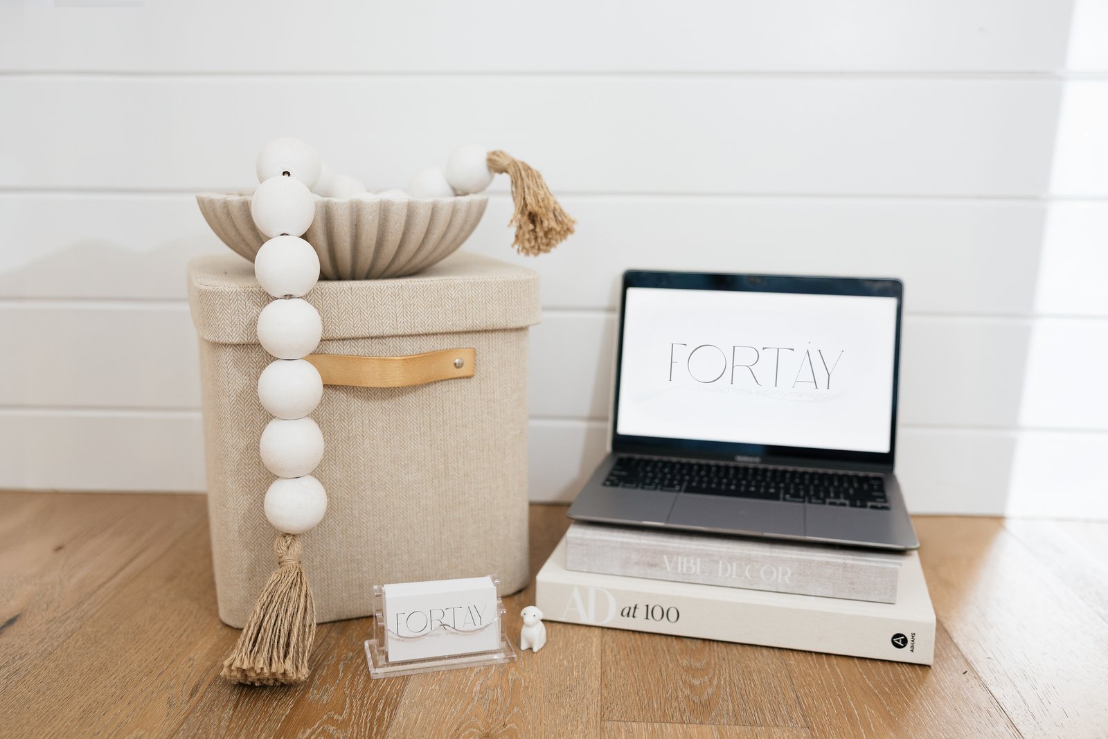 Fortáy logo on a laptop beside woven storage, design books and a business card